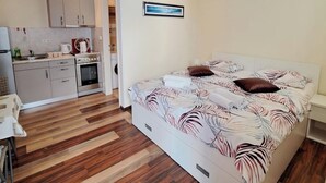 A bedroom with a bed, a nightstand, and a view of a kitchen area. - 1 Bed, Sleeps 2, Free Parking (Novigrad)