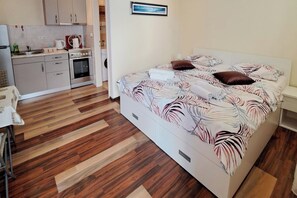 Quarto com uma cama, uma mesa de cabeceira e vista para uma cozinha.