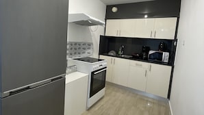 Una cocina compacta equipada con refrigerador, estufa, microondas y gabinetes.