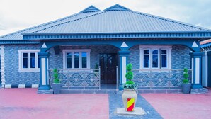 A building with a blue roof and stone facade, featuring a central entrance with a black door, flanked by two windows and decorative metal railings. - captivating 3-bed House in Ibadan oyo-state nigeri (Oyo state Nigeria)