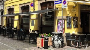 Un edificio amarillo con mesas al aire libre, un cartel de ‘no estacionamiento’ y un letrero que dice ‘Bar Magri’.