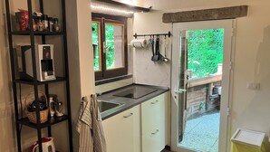 Cocina compacta con cafetera integrada, un lavabo y ventana con vistas a zonas verdes.