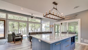 Una cocina amplia con ventanas grandes, una isla central y una lámpara moderna.