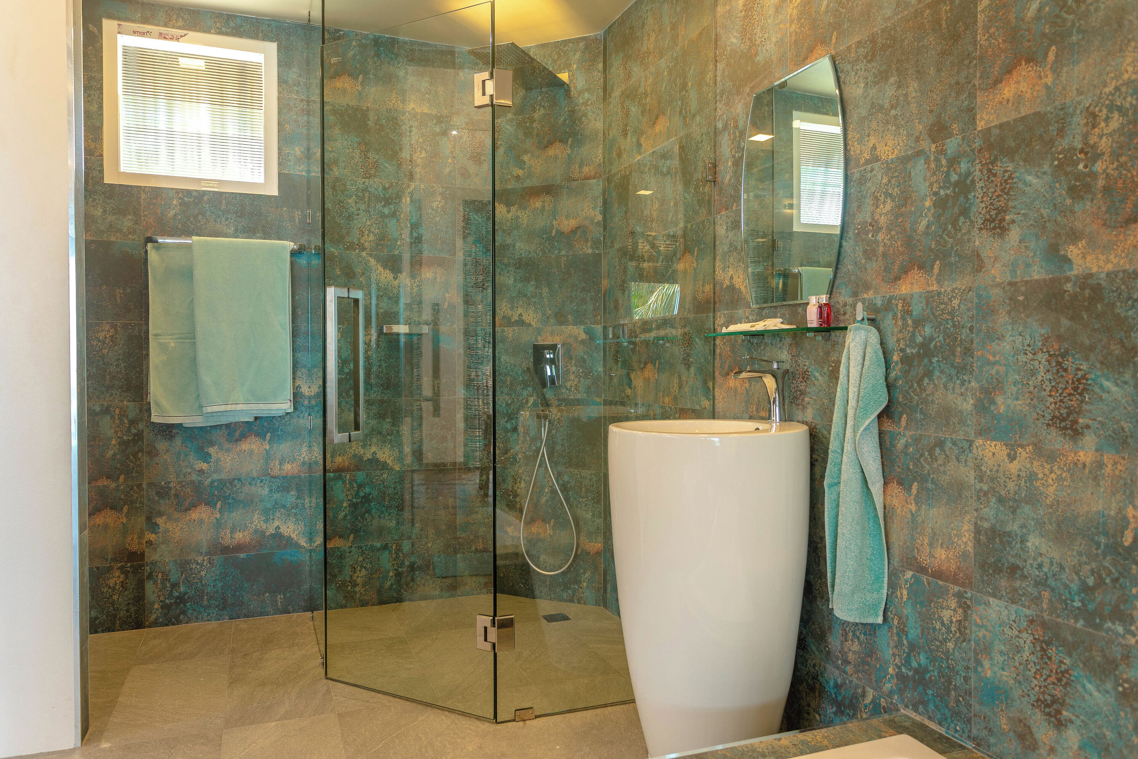A modern bathroom with a glass-enclosed shower, a large sink, and a mirror above it.