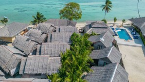 A resort with thatched-roof bungalows, a swimming pool, and a beach view. - Absolute Beachfront Resort (Ko Pha-ngan)