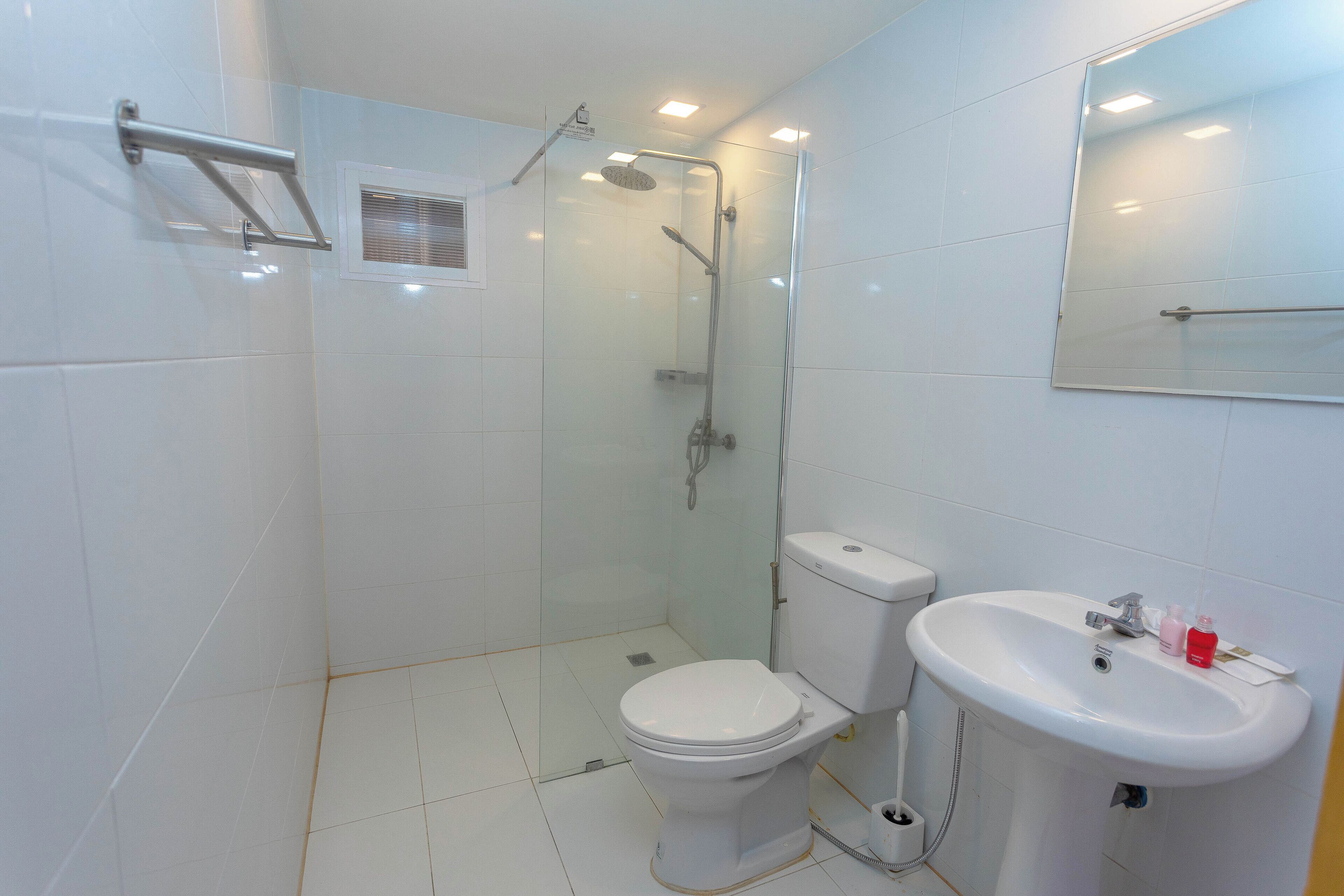 Un baño moderno con ducha de vidrio, inodoro blanco y lavamanos con espejo.
