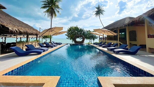 A pool with lounge chairs and umbrellas, palm trees, and a view of the ocean. - Absolute Beachfront Resort (Ko Pha-ngan)