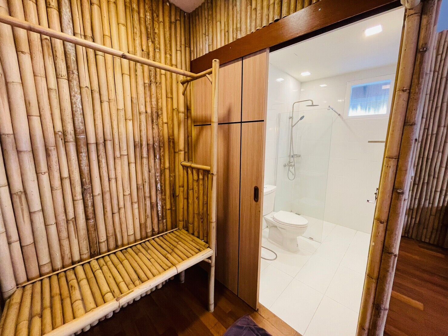 Ein Badezimmer mit Bambuswand, einer Duschkabine aus Glas und einer weißen Toilette.