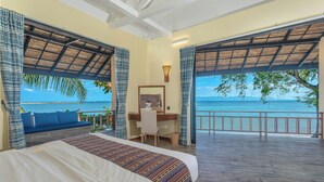 A bedroom with a large bed, a desk, and a view of the ocean. - Absolute Beachfront Resort (Ko Pha-ngan)