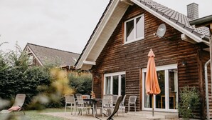 Una casa de madera con patio, mobiliario exterior y antena parabólica.