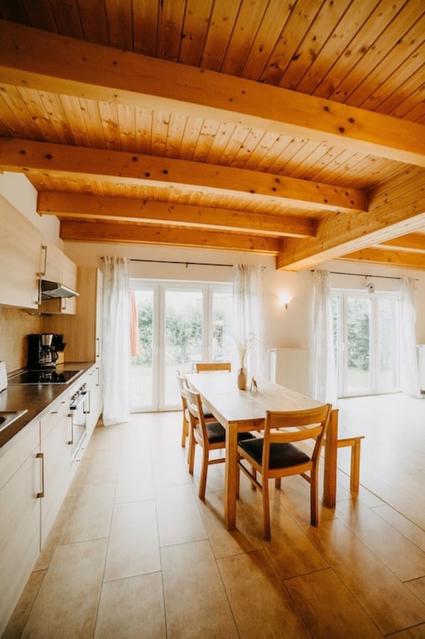 A wooden interior with a dining table, chairs, and a kitchen area. - 'Haus Mimi Zarrentin' on Lake Schaalsee with Private Terrace & Garden (Zarrentin am Schaalsee)