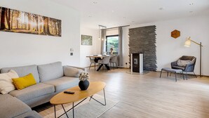 Een moderne woonkamer met een bank, salontafel en een eethoek met een tafel en stoelen.