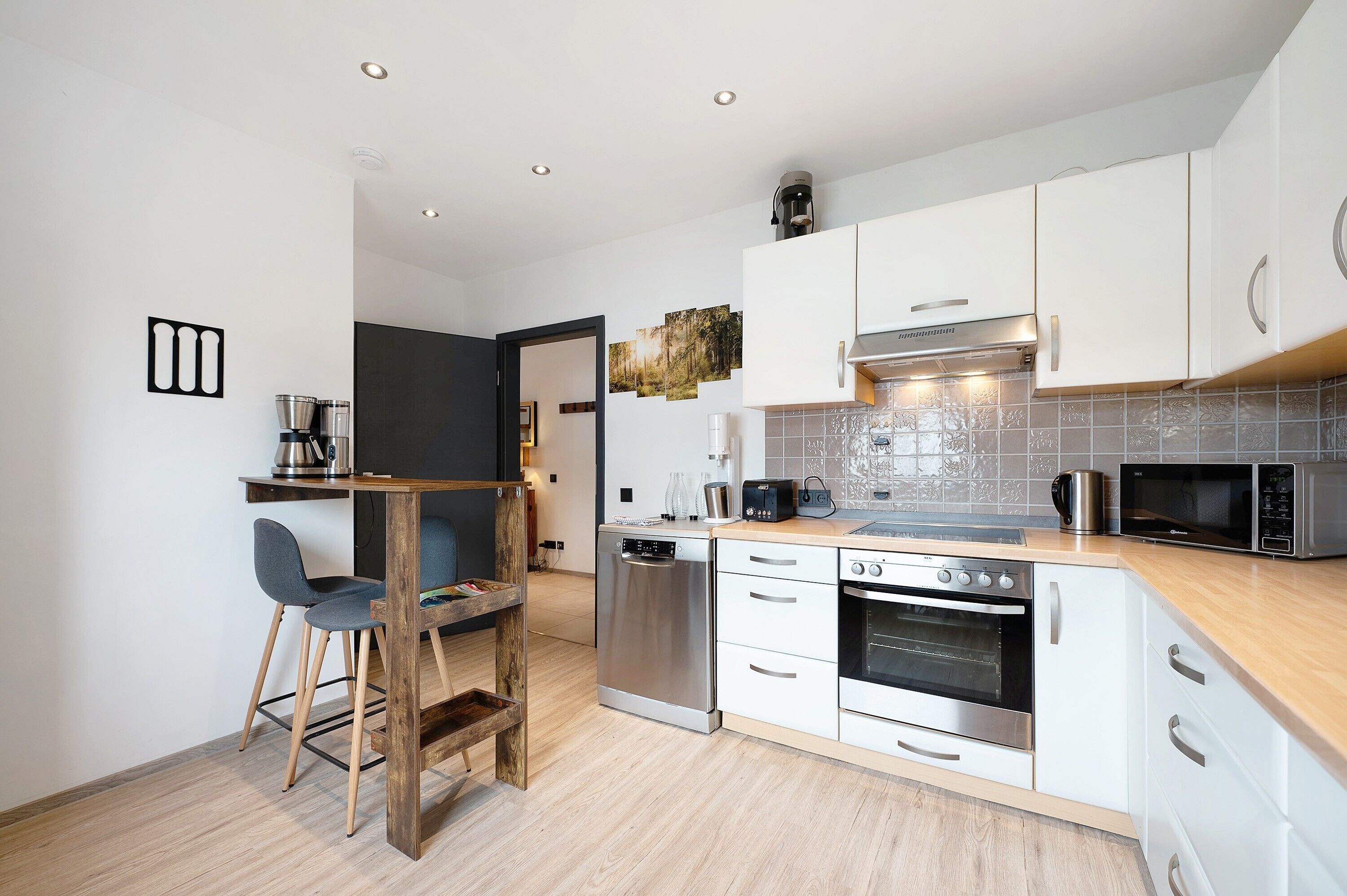 A modern kitchen with white cabinets, stainless steel appliances, and a wooden dining area.