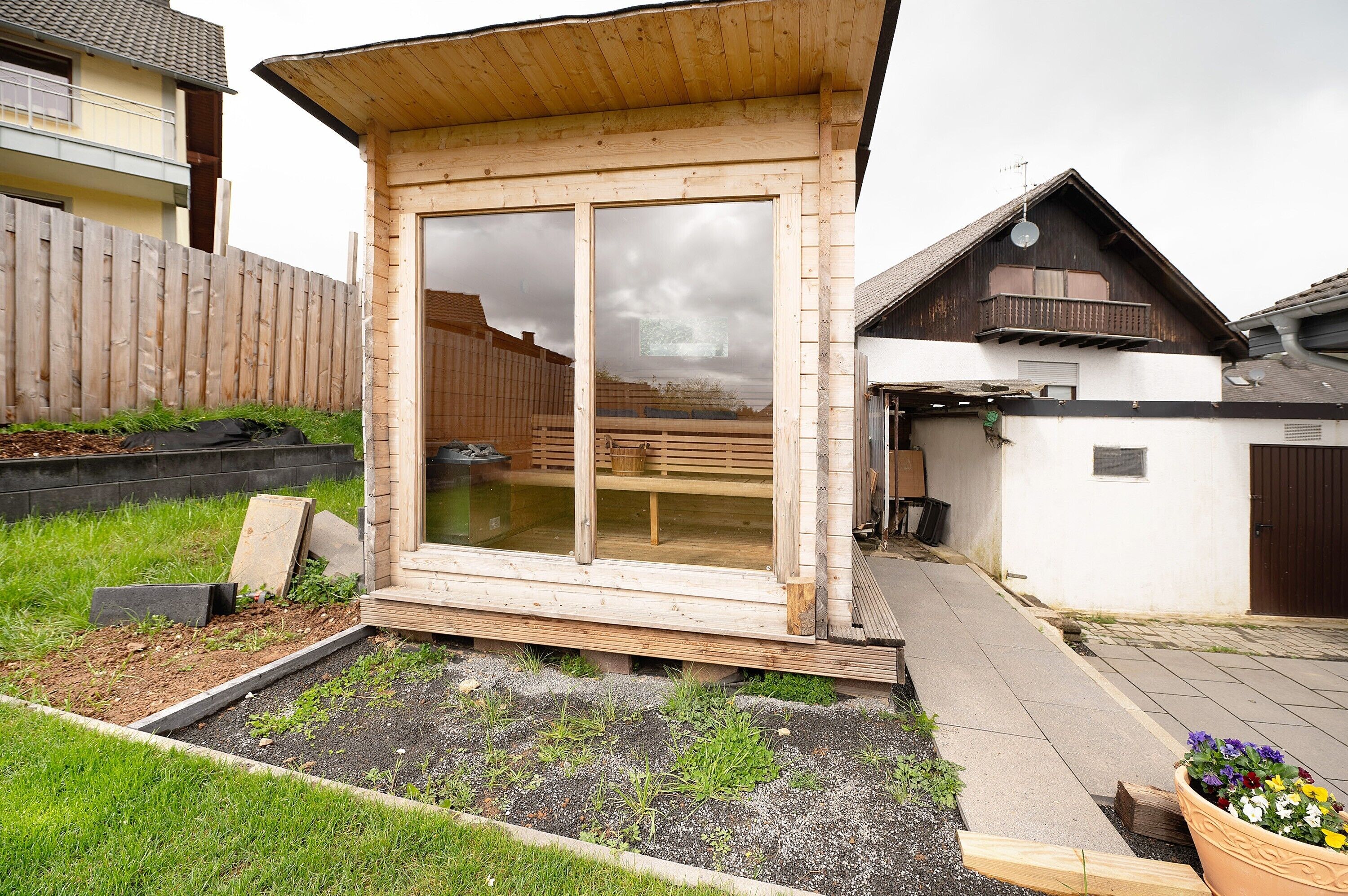 Een houten constructie met grote ramen, een houten terras en een tuin.