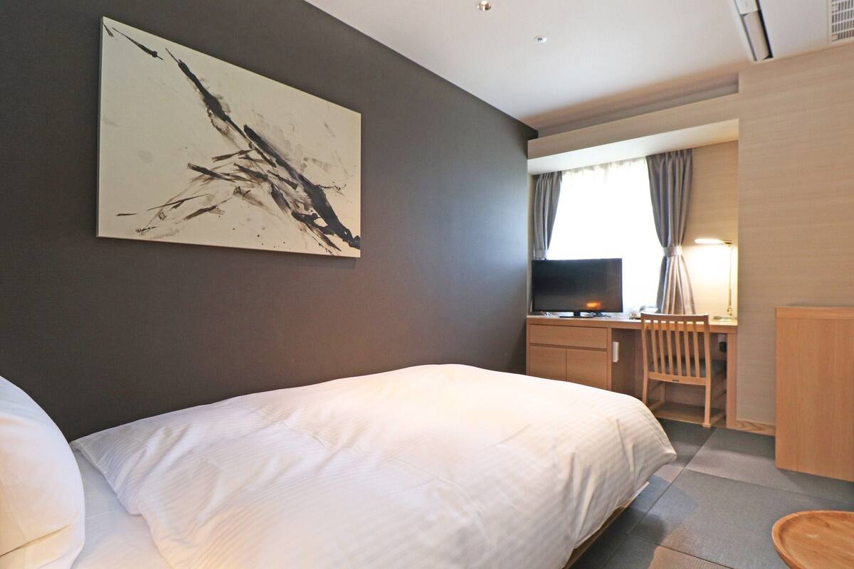A hotel room with a large bed, a desk with a computer, and a television.