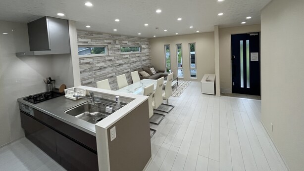 A modern kitchen with a central island, built-in appliances, and a seating area with a sofa and chairs. - shirahamakashibesso ss2-43 (Shirahama)