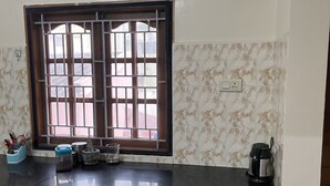 A kitchen with a black countertop, a window with metal bars, and tiled backsplash.