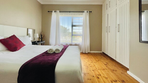 A hotel room with a bed, a nightstand, a window with curtains, and a wardrobe.