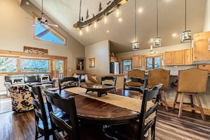 A spacious dining area with a round table, multiple chairs, and a ceiling fan.