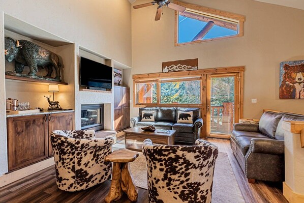A living room with a fireplace, leather sofas, and a ceiling fan.