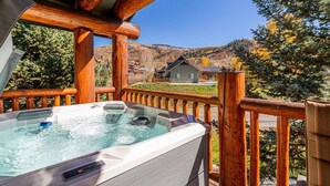 Eine Holterrasse mit Whirlpool mit Blick auf eine gebirgige Landschaft und Häuser.