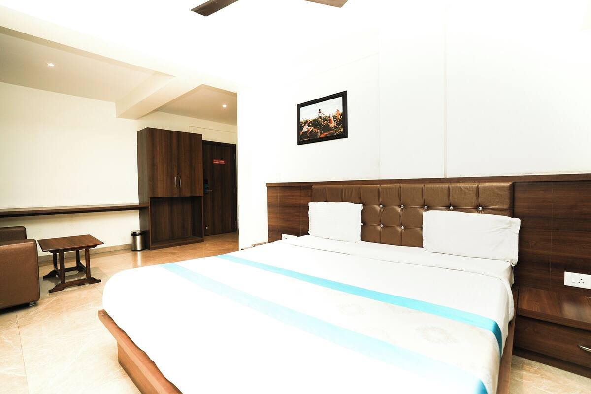 Une chambre d’hôtel avec un grand lit, une petite table, un canapé et un tableau au mur.