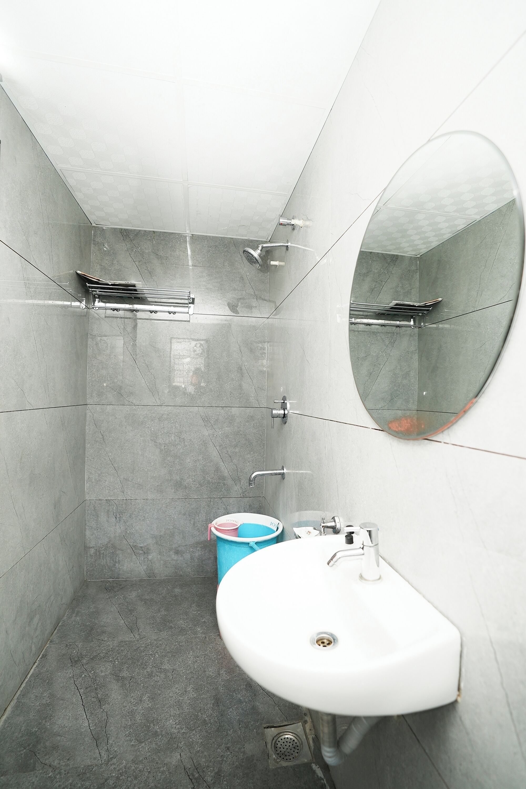 Een moderne badkamer met een witte wastafel, een ronde spiegel en een douchehoek.