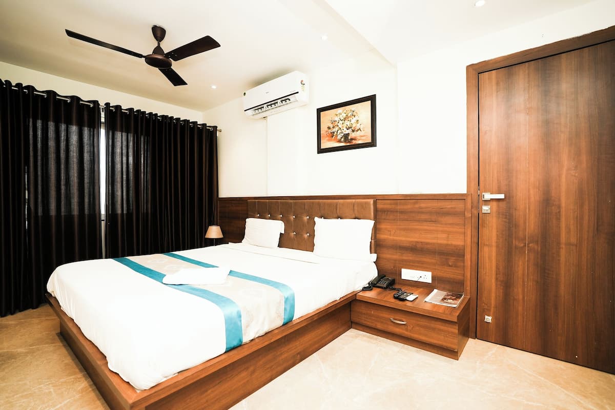 Une chambre d’hôtel avec un lit, une table de chevet et un ventilateur de plafond.