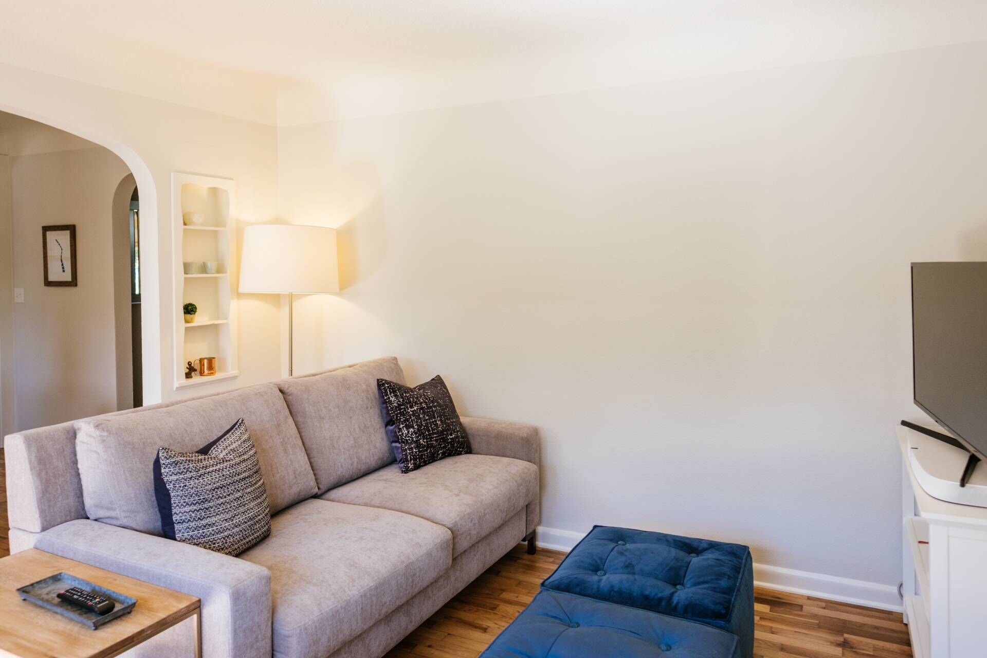 Una sala de estar con sofá, reposapiés y mueble para televisión.
