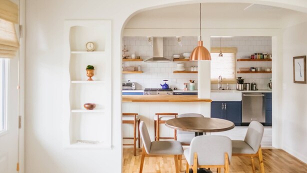 A modern kitchen with white cabinetry, a wooden dining table, and a hanging copper pendant light. - Charming Renovated Cottage, Perfect Location, Walk to Everything, Across From Park & Cultural Center (Newberg)