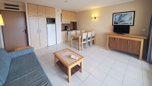 A compact living space with a kitchenette, dining area, and a TV mounted on a wooden cabinet. - CAP HERMES Magnificent air-conditioned accommodation sleeps 6 Sea view direct access to the beach with parking in the basement (Fréjus)