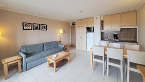 A compact living space with a sofa, a coffee table, a dining table with chairs, a kitchenette with a microwave and refrigerator, and a small side table. - CAP HERMES Magnificent air-conditioned accommodation sleeps 6 Sea view direct access to the beach with parking in the basement (Fréjus)