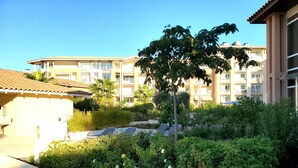 A hotel courtyard with a pool, palm trees, and a building with balconies in the background. - CAP HERMES Magnificent air-conditioned accommodation sleeps 6 Sea view direct access to the beach with parking in the basement (Fréjus)