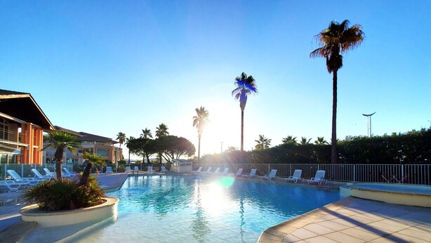 A swimming pool with lounge chairs, palm trees, and a clear sky. - CAP HERMES Magnificent air-conditioned accommodation sleeps 6 Sea view direct access to the beach with parking in the basement (Fréjus)