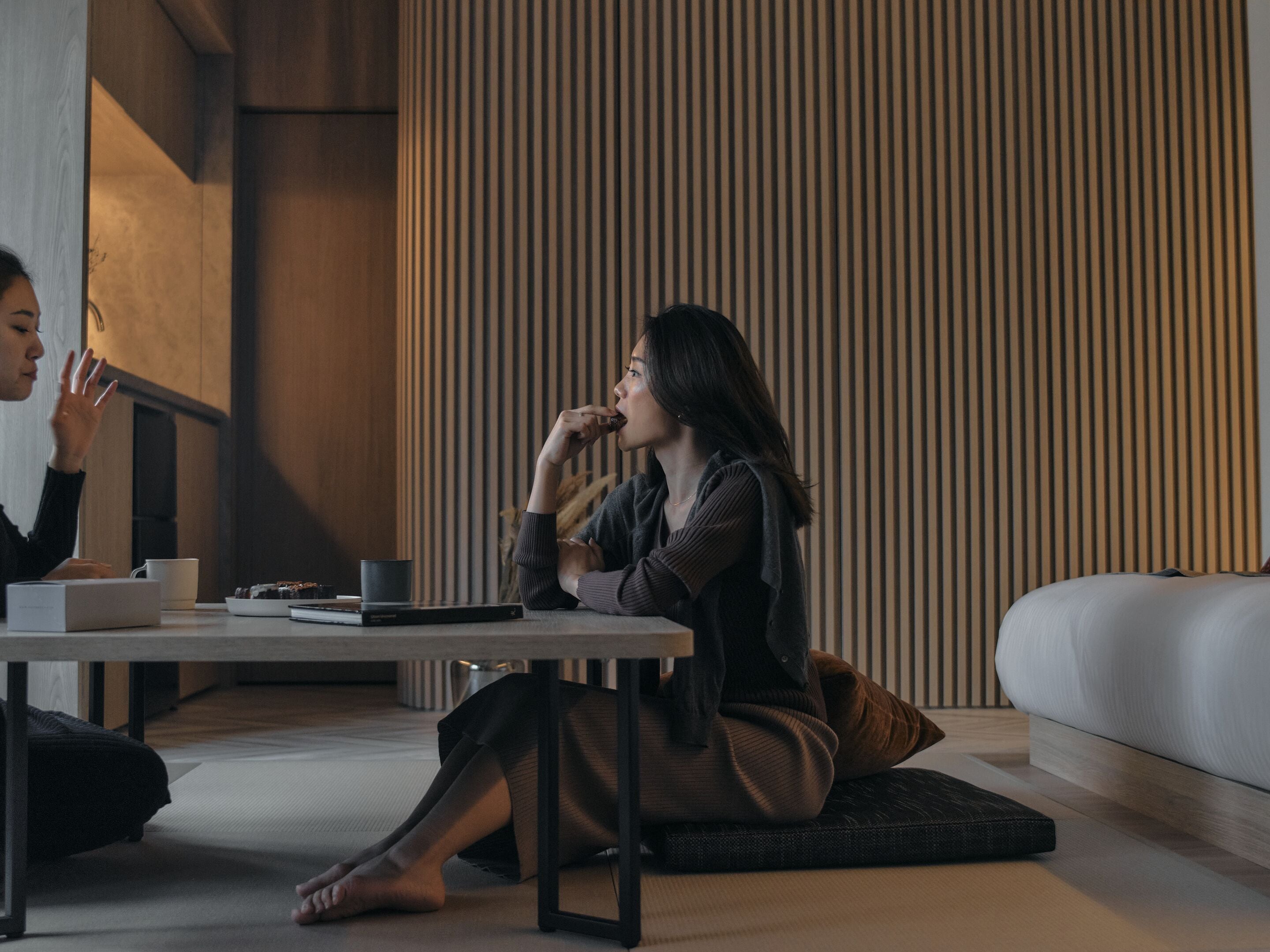 Una habitación moderna con un sofá, una mesa y una persona sentada en el suelo.