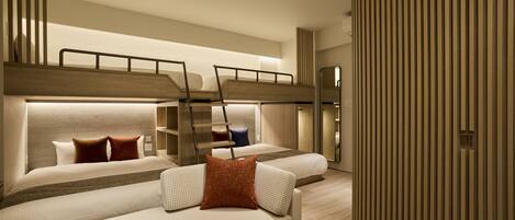 A modern hotel room with a bunk bed, a sofa, a marble coffee table, and a wooden panel wall.