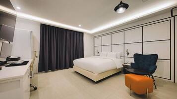 Una habitación de hotel moderna con cama, escritorio, silla y televisión.