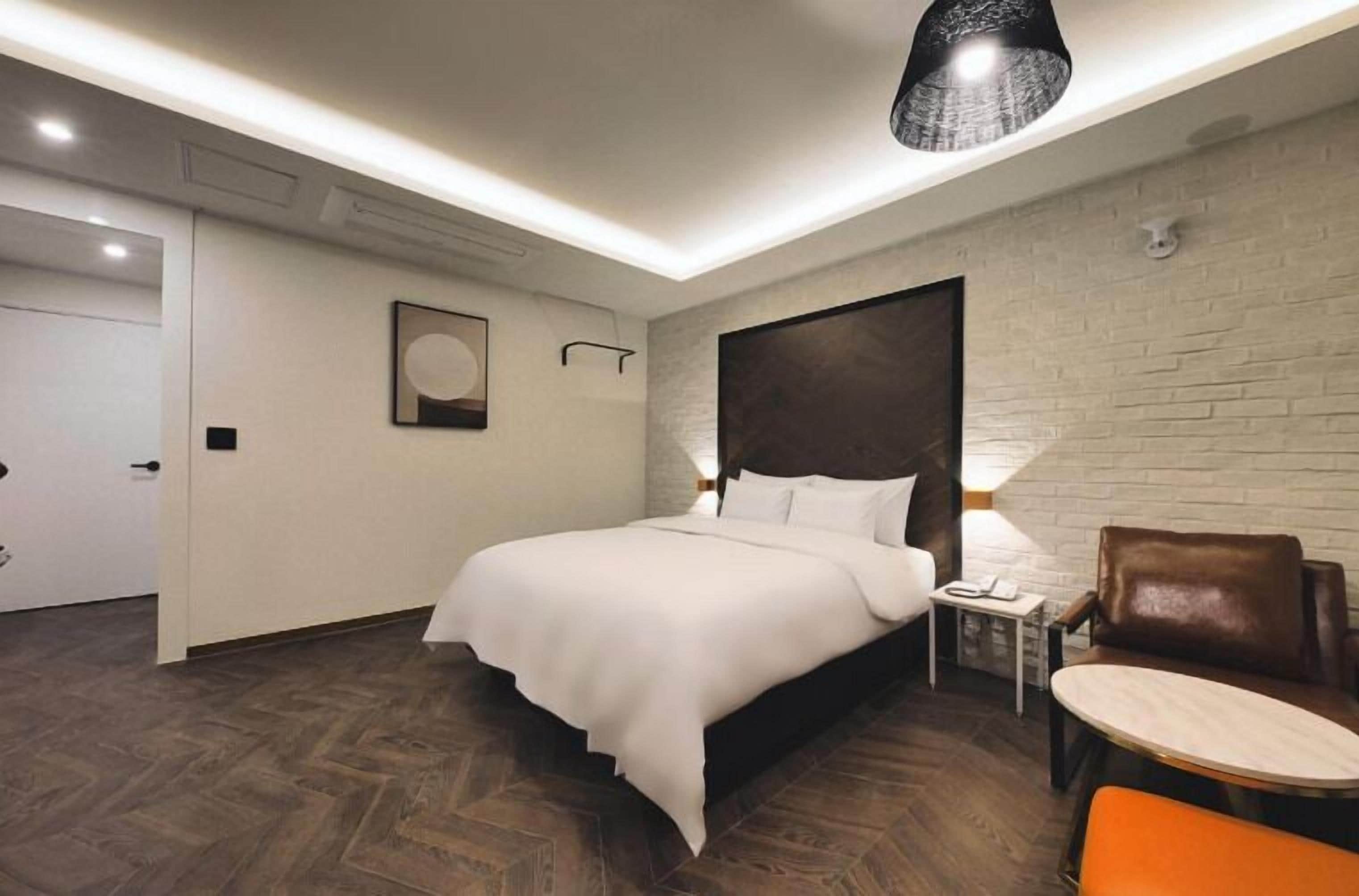 Une chambre d’hôtel moderne avec un grand lit, une petite table, une chaise et une lampe.