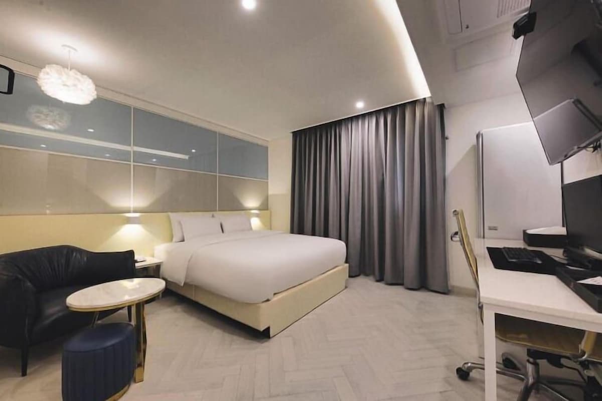Una habitación de hotel moderna con una cama, un escritorio, una silla y una mesita.