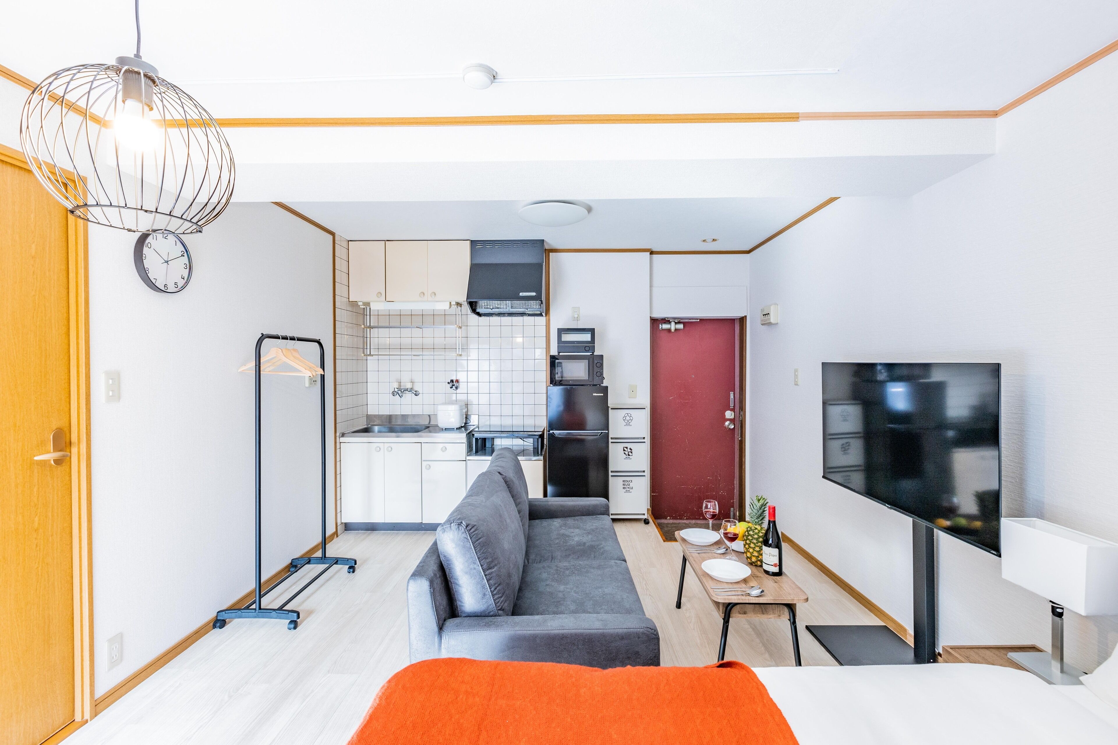 Een compacte hotelkamer met een kitchenette, een slaapbank, een televisie en een eethoek.