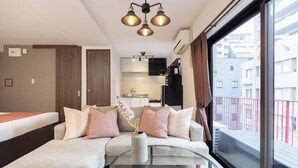 Une chambre d’hôtel moderne, dotée d’un canapé, d’une table basse en verre et offrant une vue sur la ville grâce à de grandes fenêtres.