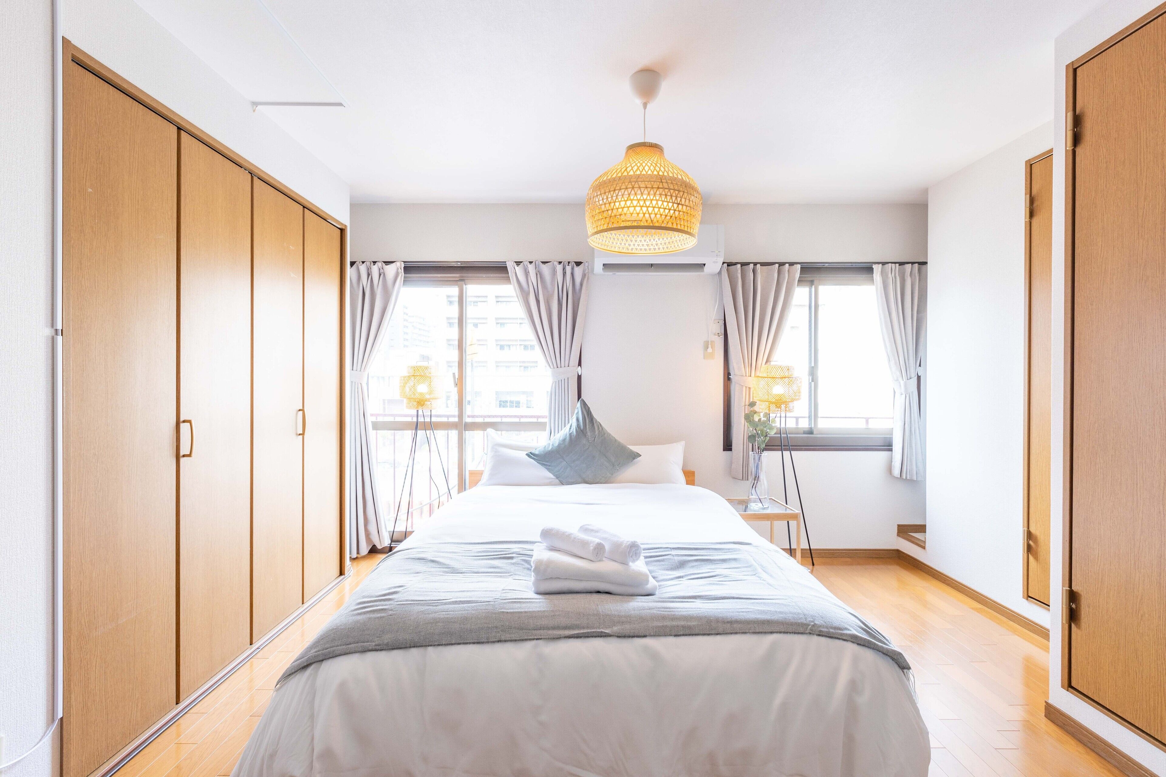 A hotel room with a large bed, wooden wardrobe, and a hanging light fixture.