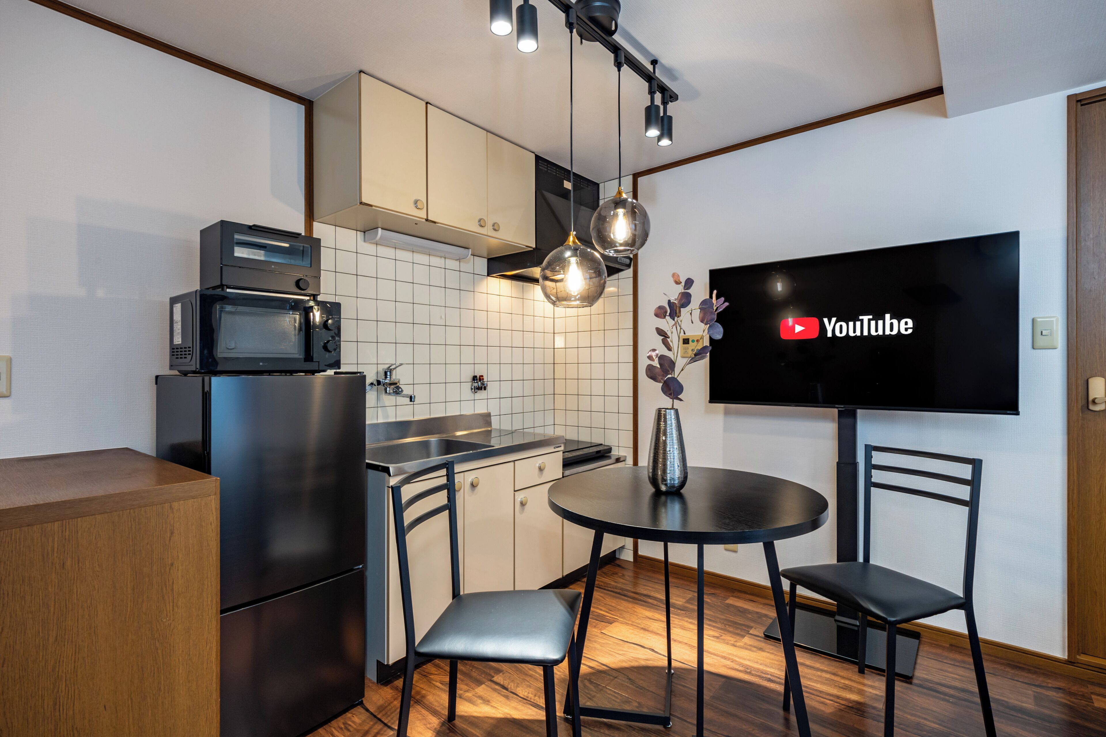A compact kitchen with a microwave, oven, and a small dining area with two chairs and a table.
