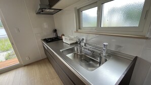 A modern kitchen with a stainless steel sink, a window above the sink, and a view of greenery outside. - shirahamakashibesso ss2-76 (Shirahama)