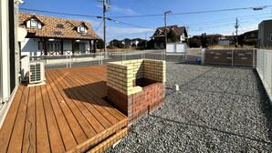 A wooden deck with a brick structure, surrounded by a gravel area and a metal fence. - shirahamakashibesso ss2-76 (Shirahama)