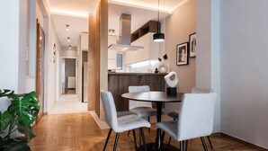 Un espace repas moderne avec une table ronde, quatre chaises et un luminaire suspendu.