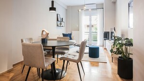 Un espace de salle à manger moderne avec une table ronde, plusieurs chaises et des luminaires suspendus.