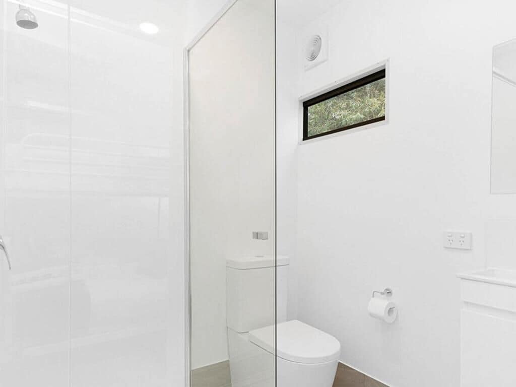 A modern bathroom with a glass shower enclosure, a toilet, and a sink.