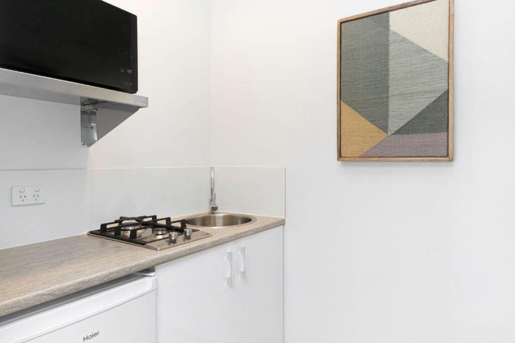 Una cocina moderna con armarios blancos, una estufa a gas y un lavamanos de acero inoxidable.