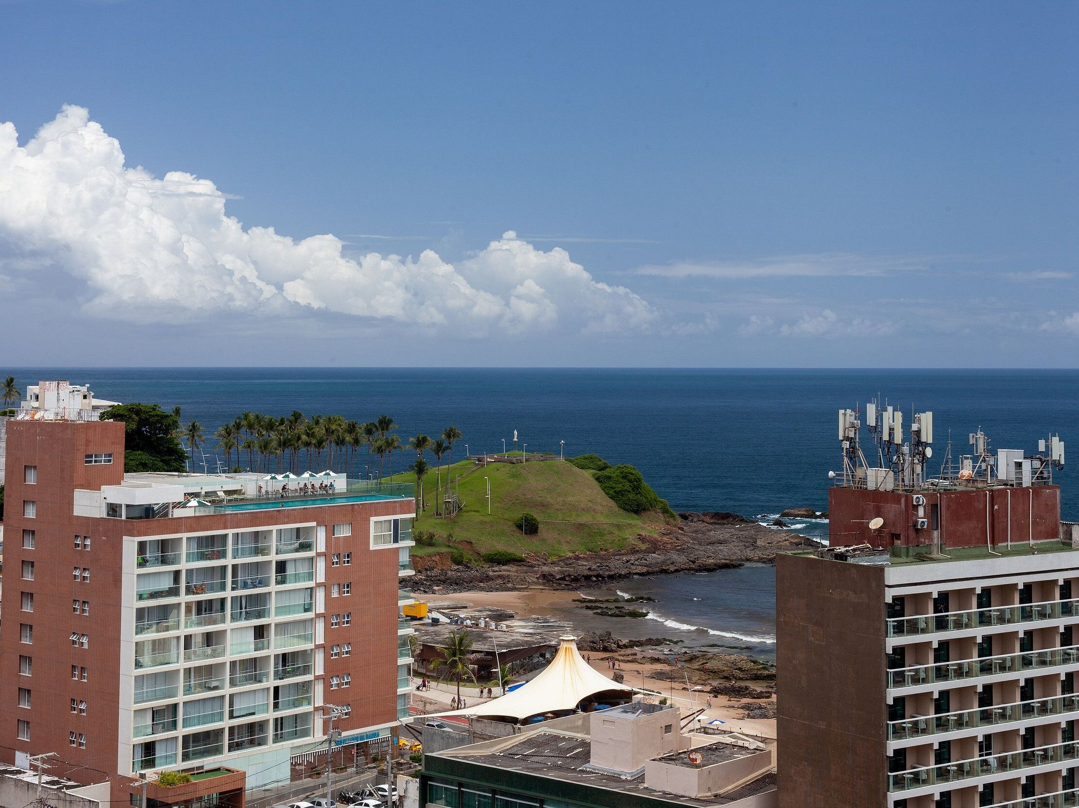 Um hotel à beira-mar com vários andares, piscina e vista para o oceano.